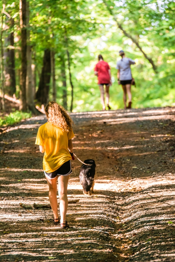 A gril walking a dog through a forest