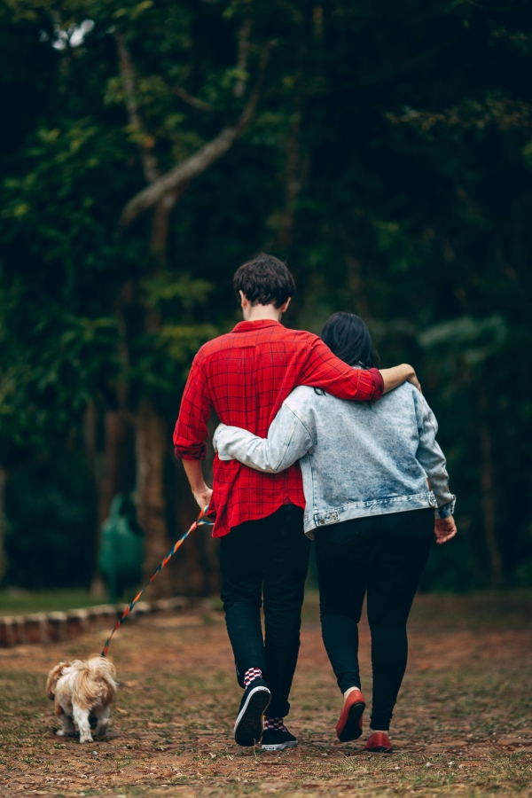 A couple walking their dog through a forest