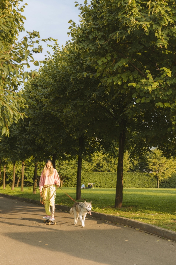 A woman walking her dog on her skateboard